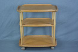 AN ERCOL ELM THREE TIER GALLERY TEA TROLLEY, with beech uprights, on casters, approximate width 71.