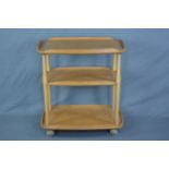 AN ERCOL ELM THREE TIER GALLERY TEA TROLLEY, with beech uprights, on casters, approximate width 71.