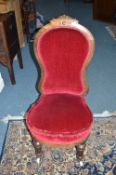 A VICTORIAN WALNUT LADIES CHAIR, upholstered in red velvet, carved top rail on fluted legs