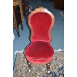 A VICTORIAN WALNUT LADIES CHAIR, upholstered in red velvet, carved top rail on fluted legs