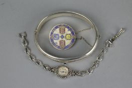 A 20TH CENTURY HINGED SILVER BANGLE, with foliate scroll decoration, together with an enamelled 1887