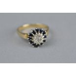 A DIAMOND AND SAPPHIRE 9CT GOLD CIRCULAR CLUSTER RING, the centre illusion set round brilliant cut