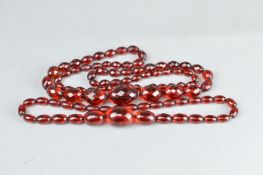 TWO STRINGS OF RED AMBER TYPE BEADS, comprising faceted graduated beads and oval graduated beads (