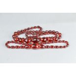 TWO STRINGS OF RED AMBER TYPE BEADS, comprising faceted graduated beads and oval graduated beads (