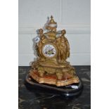 A LATE 19TH CENTURY GILT METAL MANTEL CLOCK, urn shaped finial with painted porcelain centre above