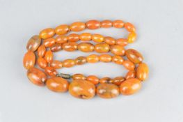A CIRCA 1920'S/1930'S NECKLACE, comprising orange bakelite oval graduated beads and metal screw