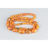 A CIRCA 1920'S/1930'S NECKLACE, comprising orange bakelite oval graduated beads and metal screw