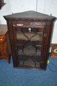 AN EARLY 20TH CENTURY CARVED OAK ASTRAGAL GLAZED HANGING CORNER CUPBOARD