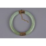 A MODERN JADE BANGLE, round hinged design with two pale green jadeite hooped sections, each capped