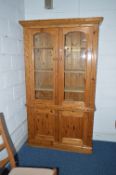 A PINE GLAZED TWO DOOR BOOKCASE, above a double door cupboard base, approximate size width 115.5cm x