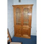 A PINE GLAZED TWO DOOR BOOKCASE, above a double door cupboard base, approximate size width 115.5cm x