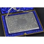 A LATE VICTORIAN SILVER RECTANGULAR CARD CASE, on short chain, floral engraved decoration with