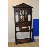 AN EARLY 20TH CENTURY CARVED OAK HALL STAND, with carved faces and foliage detail, central mirror,