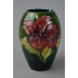 A SMALL MOORCROFT POTTERY VASE, 'Hibiscus' pattern on green gound, impressed and painted marks to