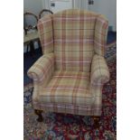 A MODERN WINGBACK ARMCHAIR, covered in stripped upholstery, on ball and claw feet