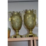 A PAIR OF BRASS PEDESTAL TWIN HANDLED VASES, decorated with storks/herons in reeds, impressed