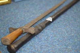 A BLACK COLOURED WOODEN WALKING CANE, possibly African in origin, carved decoration below grip,