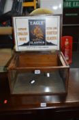A STAINED WOOD GLASS FRONTED TABLE TOP DISPLAY UNIT, with hinged lid reading Eagle Elastics to inner