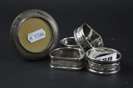 A SMALL SILVER FRAME, and two pairs of silver napkin rings