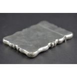 AN EDWARDIAN SILVER CARD CASE OF WAVY RECTANGULAR OUTLINE, makers F.H. Adams Ltd, Birmingham 1910,