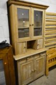 AN EARLY 20TH CENTURY PINE GLAZED TWO DOOR BOOKCASE, above two short drawers and double cupboard