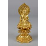 A MODERN GILT METAL SEATED BUDDHA, pierced oval head rest, seated cross legged on a multi tier