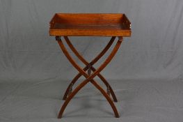 A LATE VICTORIAN MAHOGANY BUTLERS TRAY ON FOLDING STAND, the rectangular tray with cut away handles,