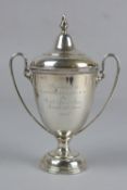 AN EDWARDIAN SILVER TWIN HANDLED TROPHY CUP AND COVER, knop finial above a dome, the cup engraved '