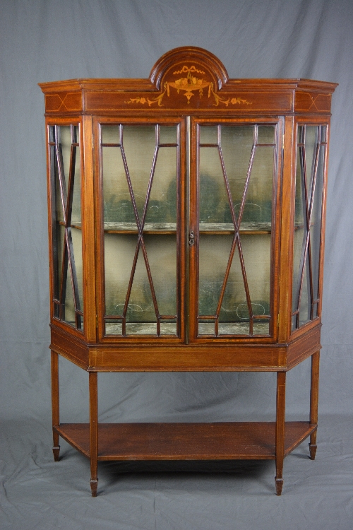 AN EDWARDIAN MAHOGANY AND INLAID DISPLAY CABINET, of triangular form, the cornice with central