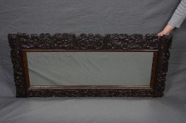 A LATE 19TH CENTURY CARVED OAK FRAMED MIRROR, of rectangular form, with foliate scrolls, exotic