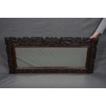 A LATE 19TH CENTURY CARVED OAK FRAMED MIRROR, of rectangular form, with foliate scrolls, exotic