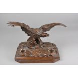 A LATE 19TH CENTURY BLACK FOREST DESK STAND, carved as an Eagle with wings outstretched on a rocky