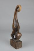 A CARVED HARDWOOD FIGURAL ORNAMENT, in the form of a two legged scaly lizard with monkey face,