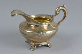 A WILLIAM IV SILVER CREAM JUG, of squat baluster form, gilt interior, cast 'S' scroll handle, on a