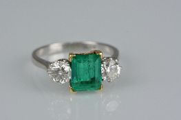 A LATE 20TH CENTURY EMERALD AND DIAMOND THREE STONE RING, white metal claw setting, emerald cut