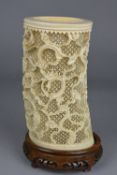 A LATE 19TH CENTURY IVORY BRUSH POT, with carved decoration of dragons on an intricately pierced
