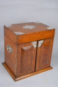 AN EDWARDIAN OAK AND SILVER PLATED TANTALUS BOX, of rectangular form, the hinged cover and double