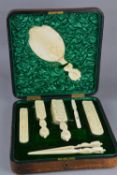 A LATE VICTORIAN LEATHER CASED IVORY DRESSING TABLE SET, comprising hand mirror, glove stretchers,