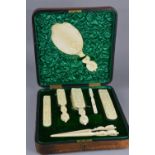 A LATE VICTORIAN LEATHER CASED IVORY DRESSING TABLE SET, comprising hand mirror, glove stretchers,