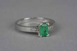 A MODERN EMERALD AND DIAMOND DRESS RING, one emerald cut emerald measuring approximately 5.9mm x