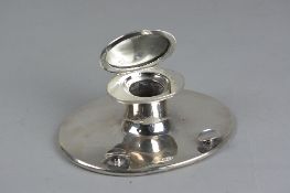 A GEORGE V SILVER CAPSTAN INKWELL, of oval form, hinged cover, no internal liner, the loaded base