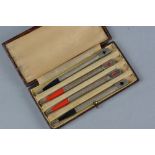 A CASED SET OF FOUR STERLING SILVER BRIDGE PENCILS, the square finials enamelled with card suit to