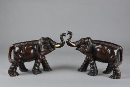 A PAIR OF LATE 19TH CENTURY ORIENTAL CARVED WOODEN ELEPHANTS, with trunks raised, glass eyes,