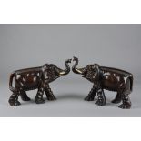 A PAIR OF LATE 19TH CENTURY ORIENTAL CARVED WOODEN ELEPHANTS, with trunks raised, glass eyes,