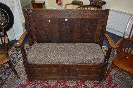 A GEORGIAN CARVED OAK HALL SETTLE, with triple panel back and hinged storage compartment,