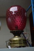 A LARGE BRASS BASED TABLE LAMP WITH DIMPLED CRANBERRY GLASS SHADE, height approximately 50cm