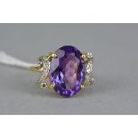 A MODERN DIAMOND AND AMETHYST DRESS RING, centring on a large oval mixed cut amethyst, measuring