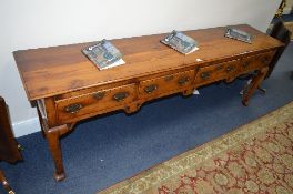 A REPRODUCTION YEW WOOD DRESSER BASE, of four short drawers with brass handles and escutcheons,