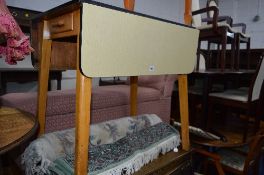 A FORMICA TOPPED DROP LEAF TABLE, with a single drawer, a woollen rug, green, black and red