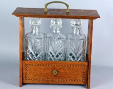 AN ARTS & CRAFTS OAK AND INLAID TANTALUS, with brass carry handle to the top above an open frame